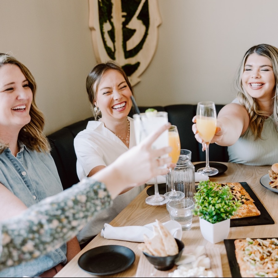 a group of women sitting at a table with food and drinks