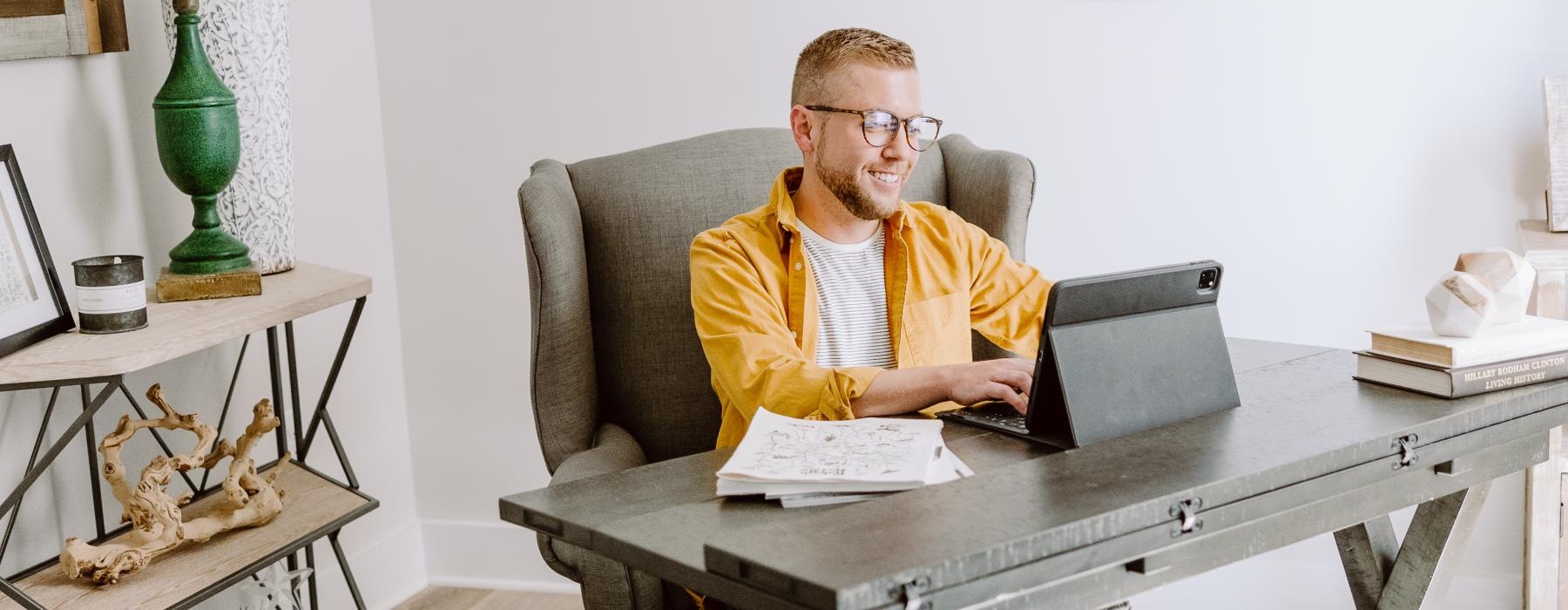 a person sitting in a chair with a laptop and a dog